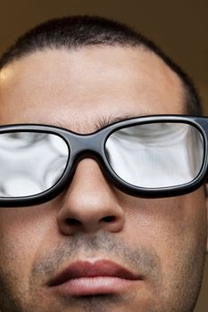 Close view of the face of a man with dark thick glasses.
