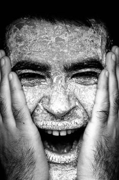 Close up view of a man's hands on the face covered in flour, screaming.