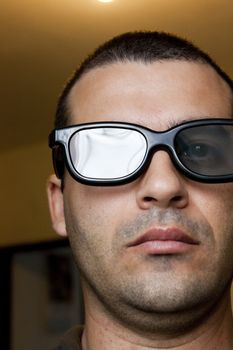 Close view of the face of a man with dark thick glasses.