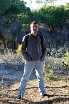 Young man with a backpack with hands on pockets on the forest.