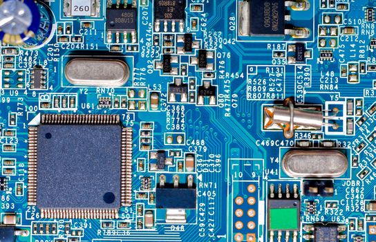 Close-up photograph of the microchips and micro-electronic components on a blue circuit board