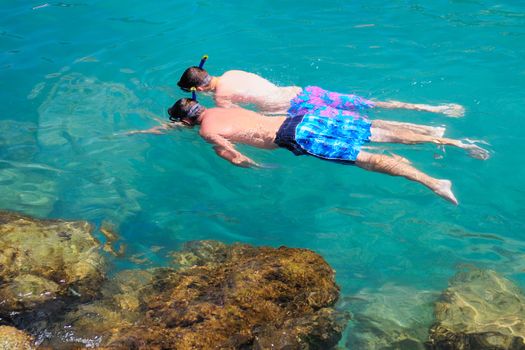 Two tourists snorkeling in clear sea water