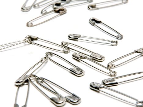 Several safety pins on a studio background