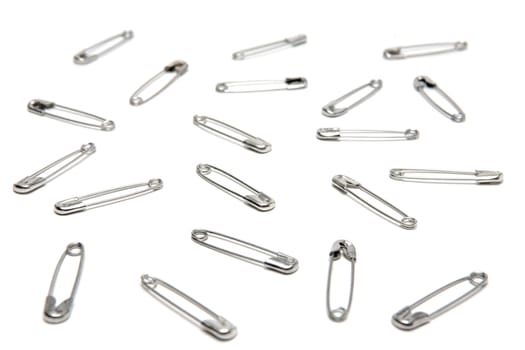 Several safety pins on a studio background