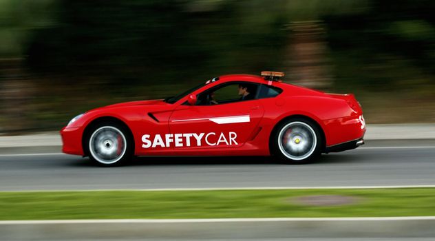 Side view of a red sport safety car driving fast on a road.