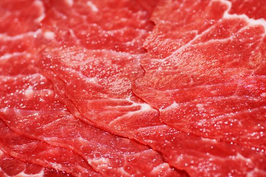 Close up of thin sclices of uncooked red meat for chinese fondue.