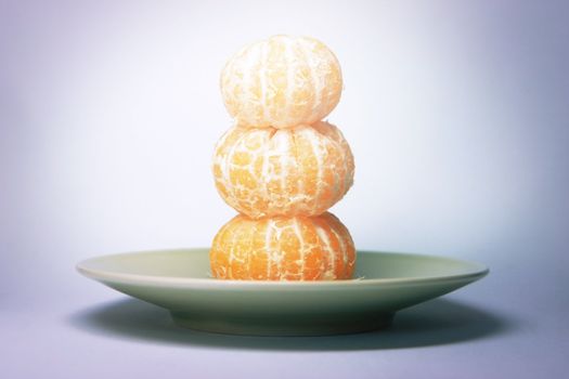 Three tangerines top of each other on a plate