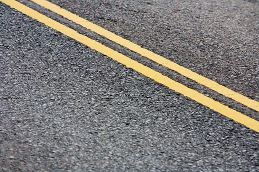 Yellow lines in road made of asphalt