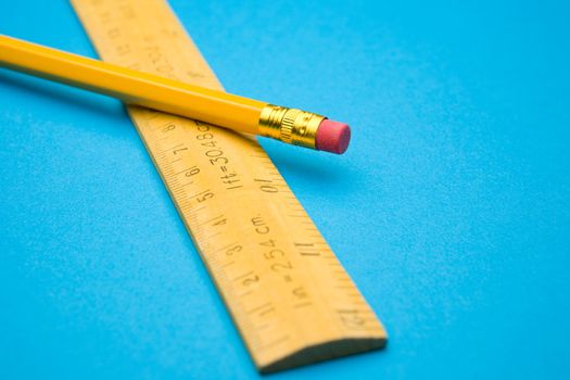 Wooden ruler and pencil on a blue background