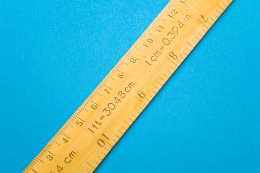 Yellow wooden ruler on blue background