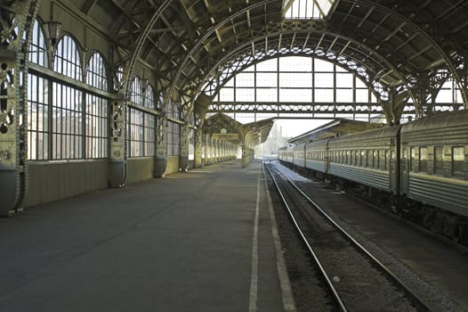 Railroad station platform with a hanging clock and "Have a nice trip" signboard.