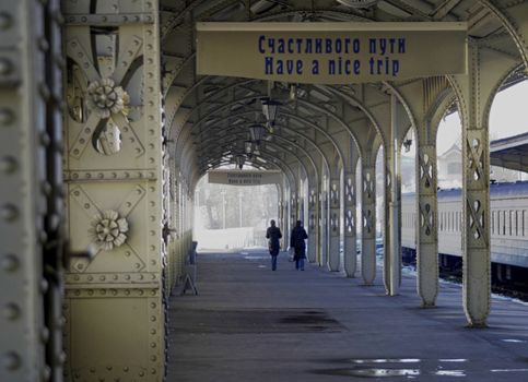 Railroad station platform with a hanging clock and "Have a nice trip" signboard