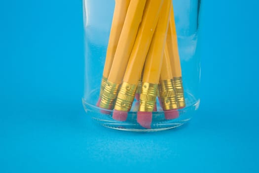 Yellow pencils in jar on blue background