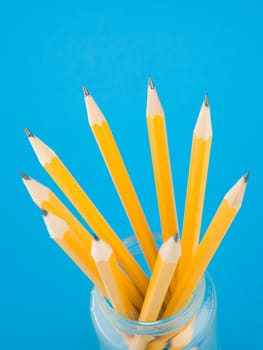 Yellow pencils in jar on blue background