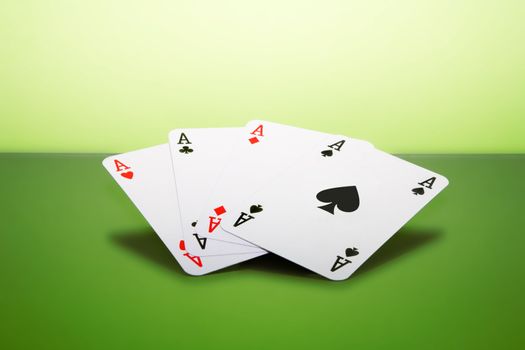 Four playing cards - aces - on a green surface