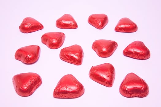 Chocolate heart candies forming a bigger heart shape on a white background