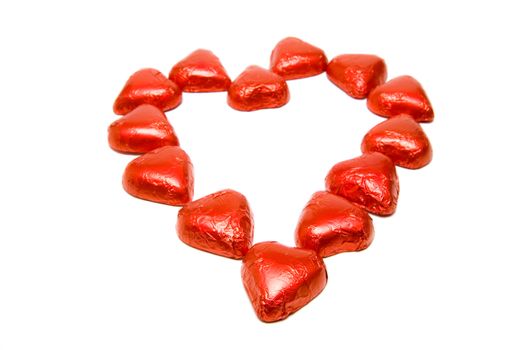 Chocolate heart candies forming a bigger heart shape on a white background