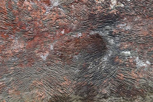 Red-colored corroded wall with surface ridges