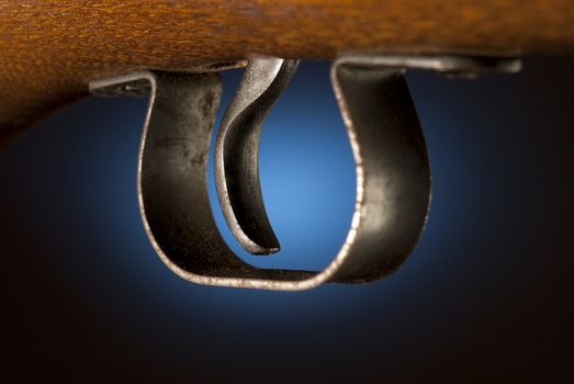 Trigger of a rifle back lit by blue spot