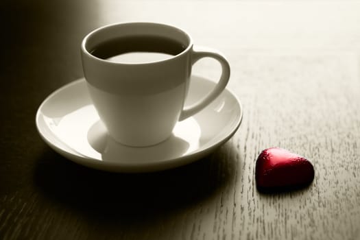 Cup of black coffee and a chocolate heart