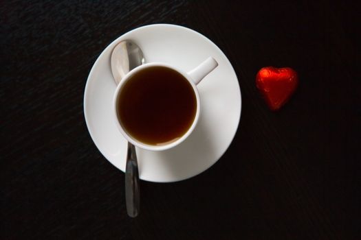 Cup of black coffee and a chocolate heart