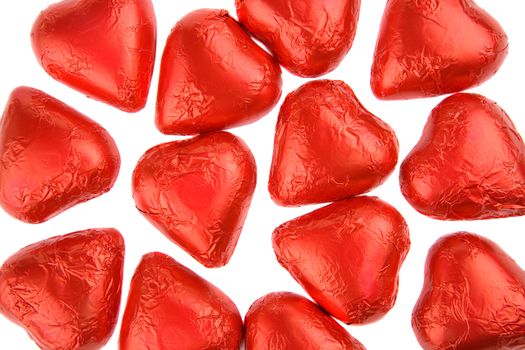 Heart shaped chocolate candies with red wrappings on a white background
