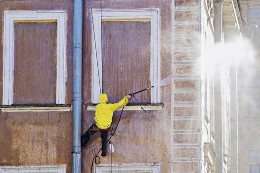 Cleaning service worker washing old building facade