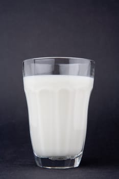 Milk in glass over dark grey background