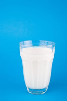 Milk in glass over blue background