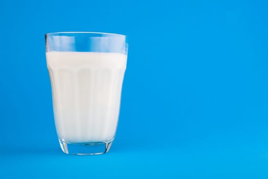 Milk in glass over blue background