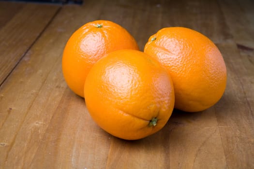 Three oranges on a wooden table