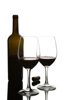 Two glasses of red wine and a translucent bottle