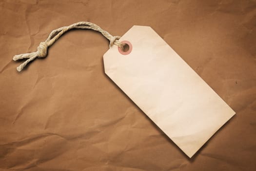Blank tag label with cotton string over brown paper background