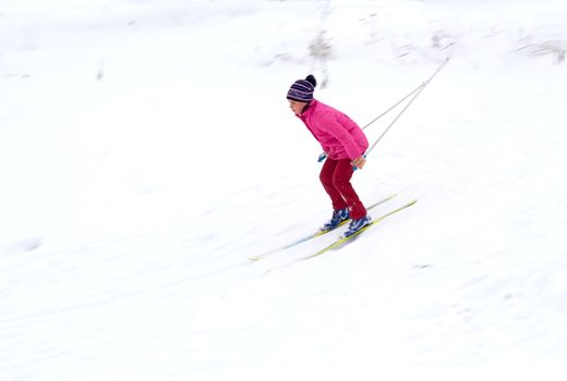 Little girl skiing fast down the hill in snow winter day