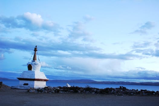 Landscape of a white stupa by a lake in Tibet