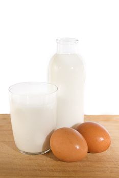 Brown eggs and some milk in glass and bottle on white