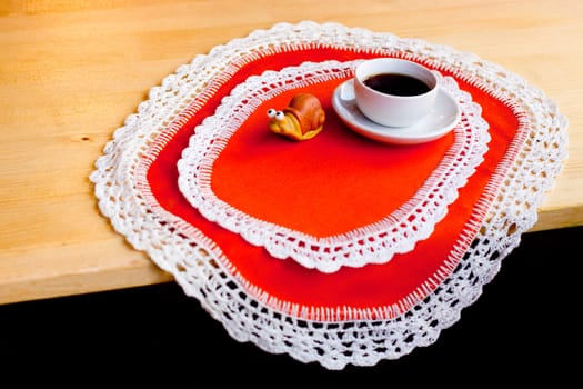 A coffee cup and a toy on two orange napkins

