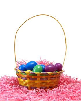 A Easter basket filled with eggs on some pink paper shreds.