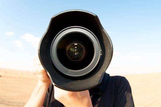 Front view of a lens of a man taking photo in the Dubai Desert, United Arab Emirates