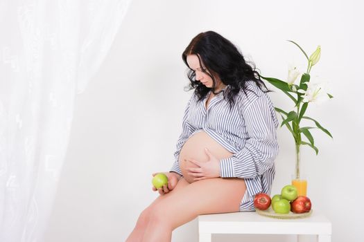 pregnant girl, apples and lilies. Studio photography
