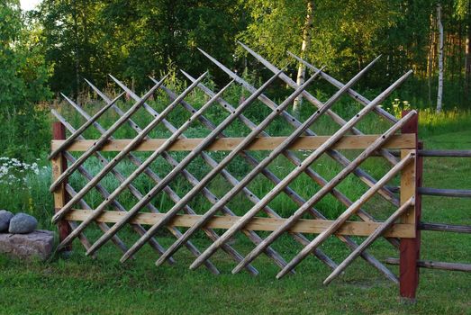 Old wooden stylish fence on green grass lawn