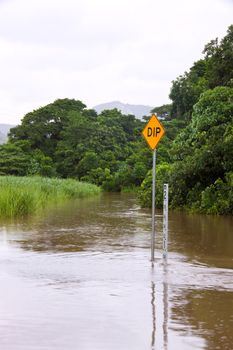 Flooded road with depth indicators and dip sign in Queensland, Australia