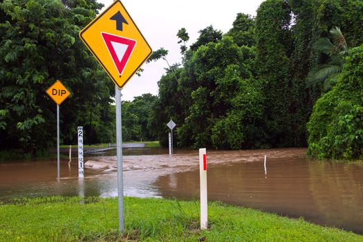 Flooded road with depth indicators and give way and dip road signs  after heavy rain and flooding in Queensland, Australia
