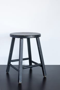 Painted black shabby stool on wooden surface.