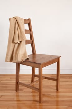 Colors of natural wood. Chair on wooden floor with clothing put over its back.
