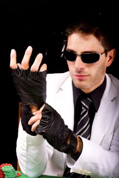 View of a gangster man playing some cards and poker, adjusting the gloves.