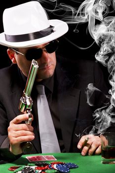 View of a gangster man playing some cards and poker, smoking a Cuban cigar.