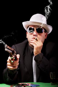 View of a gangster man playing some cards and poker, smoking a Cuban cigar.