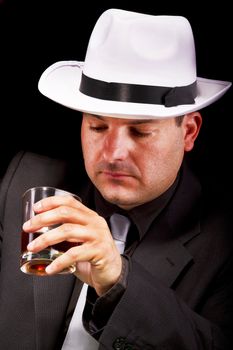 View of a gangster man with white hat drinking some liquor.