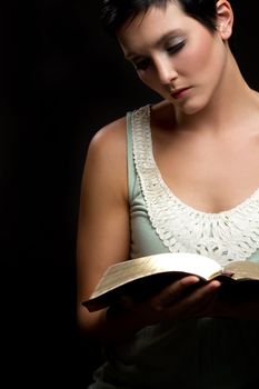 Beautiful young woman reading bible